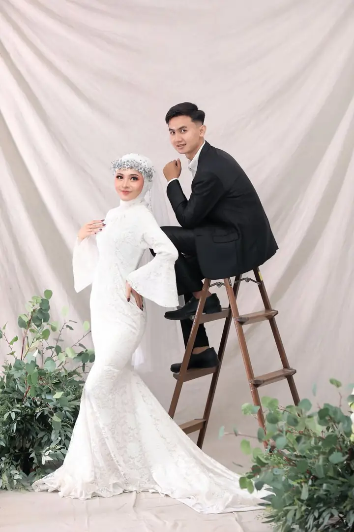 Putri bergaun putih dan Willy berjas hitam duduk di tangga kayu